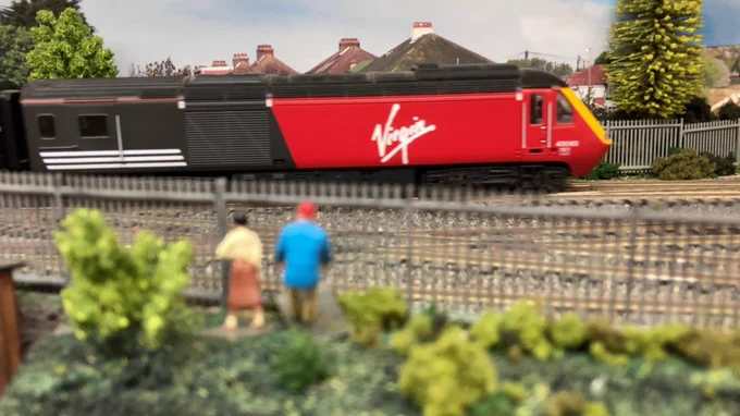 Model railway scene with couple looking through fence at Virgin Intercity 125