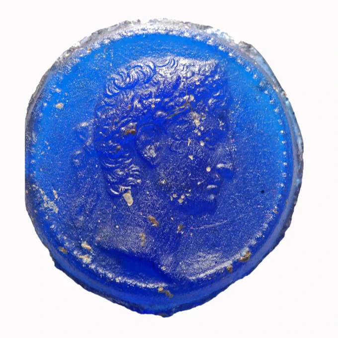 Cameo of deep blue glass paste, engraved with a laureate head of Augustus in profile; the rim is milled like that of a coin.