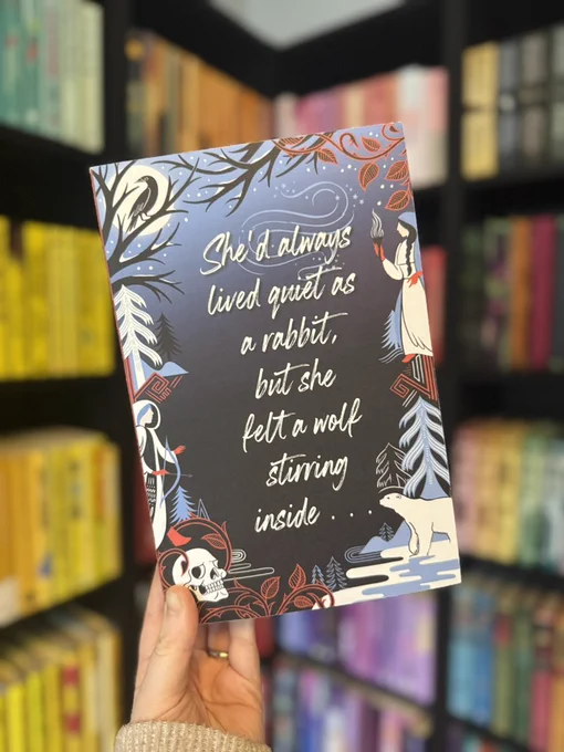 North is the Night by Emily Rath held up in front of a book case filled with books. 