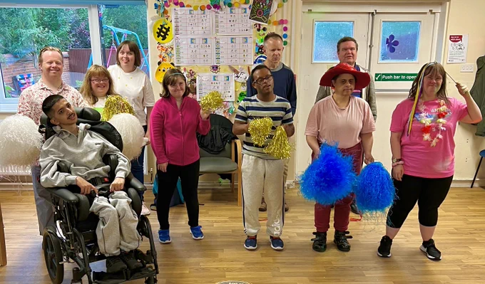 Five men and five women who attend Reading Mencap's day service are taking part in a dance session and shaking gold, blue and white tassels.
