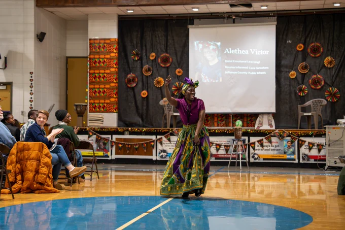 A woman smiles and dances in front of an audience.