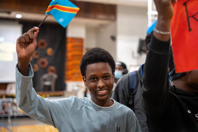 A student smiles and waves a flag.