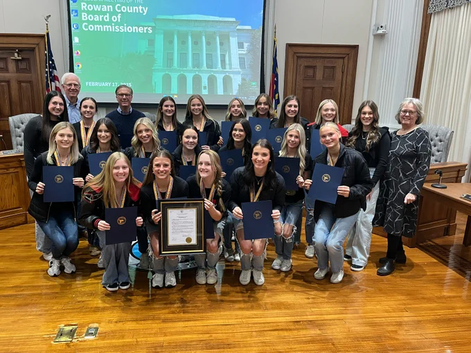 Group of young women hold their proclamations posing with three elected officials in front of the dais in the Board chambers.
