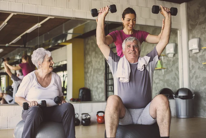older adults strength training in gym, lifting weights