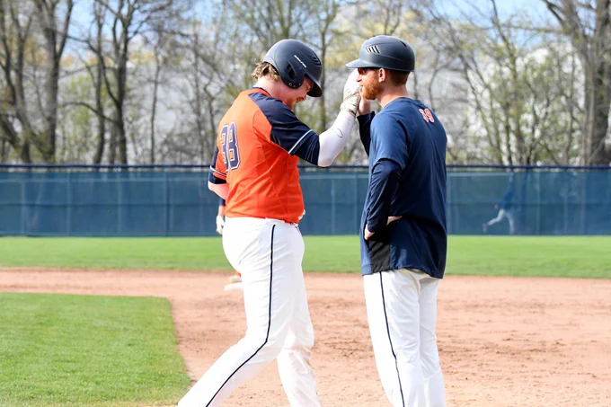 First base coach Ryan Dorow gives a high-five.