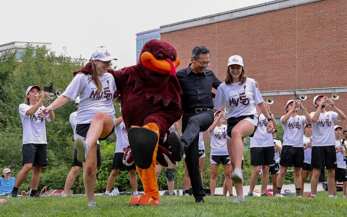 Dean Liu, HokieBird, and the Marching Virginians perform the Hokie Pokey outside on Henderson Lawn.