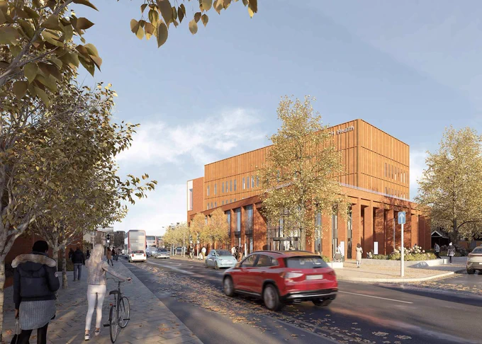 Image shows a mockup of what the iREACH building will look like once completed, from the side on. It features traffic passing in front of the building and pedestrians walking past it.
