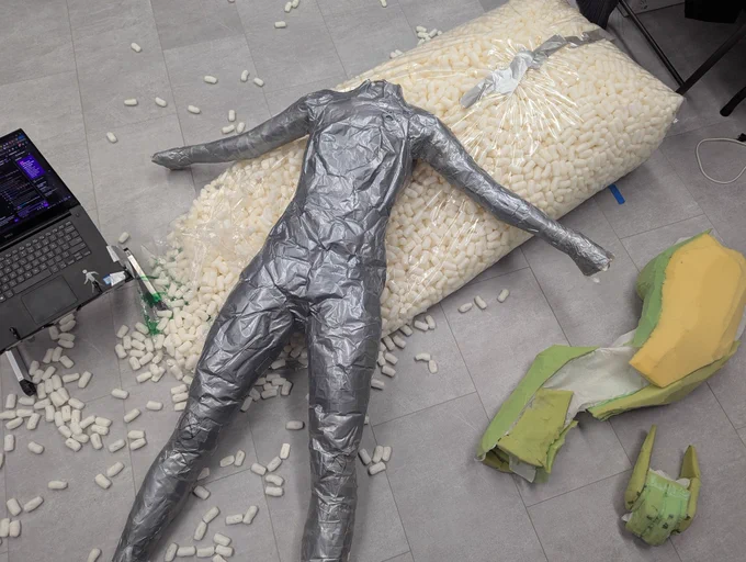 Duct tape dummy on the floor with a giant bag of packing peanuts