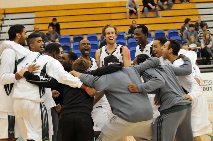 Celebrating victory against Lethbridge in 2013, team members cheer while standing in a huddle.