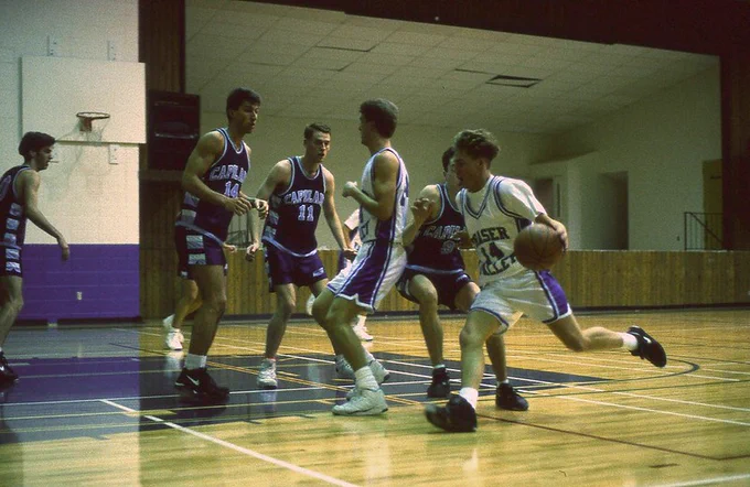 The Cascades in action in 1992, before we had our own gym. Two players wearing white jersies approach three players wearing blue jersies, while dribbling the ball.