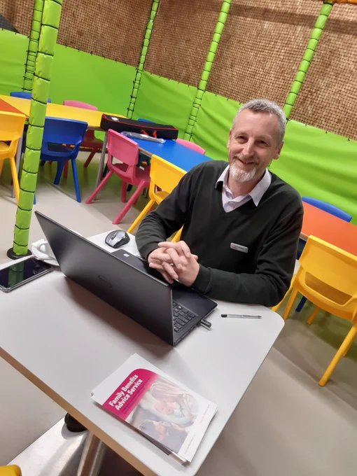 Chris Briggs Family Benefits Advice Service at a laptop in High Rise Lisburn
