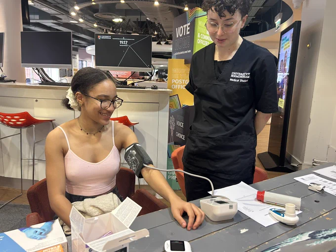 Image of two students with one of them having a blood pressure check during Student Volunteering Week.