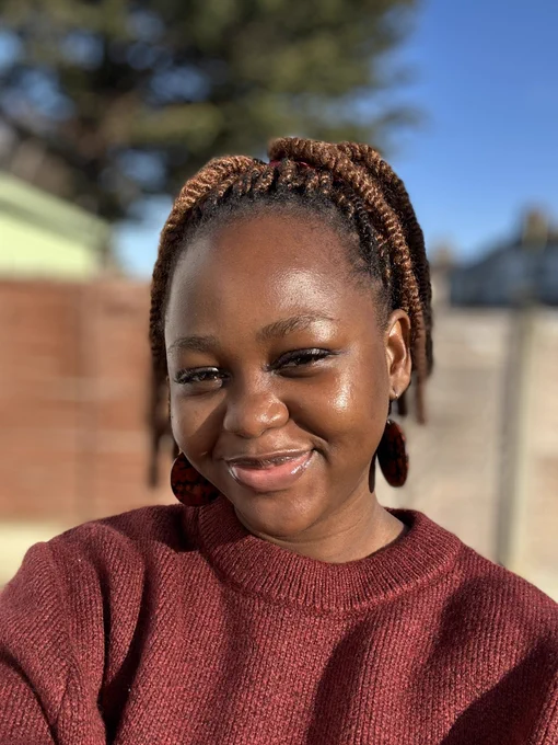 A portrait image of Liz wearing a wine/burgundy sweater, she’s smiling.