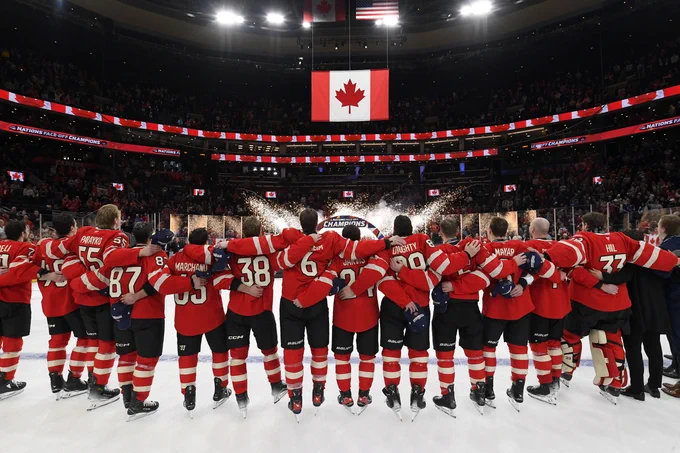 All the Canada players on ice side-by-side singing O Canada and looking up at the Canadian flag