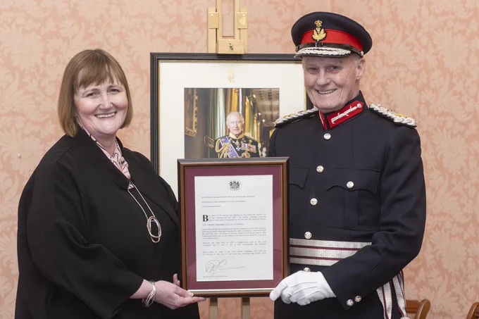 Donella Beaton and the Lord Provost, in full regalia, stand with a framed letter of Donella's confirming her appointment. 