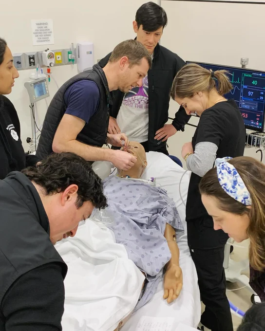 Six doctors work on a simulation manikin.