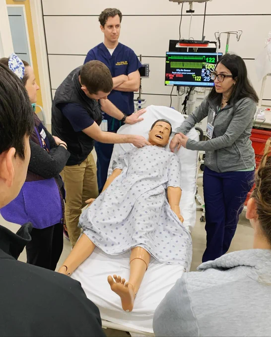 Six emergency medicine doctors work on a simulation manikin.