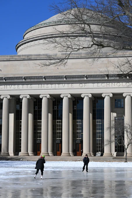 Two students skate on a patch of ice in front of MIT's dome.
