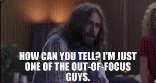 Jason Lee in the movie “Almost Famous.”  He has long brown hair and a mustache and beard. He is standing in a room with a lamp behind him. He looks irritated. The text says, “How can you tell?  I’m just one of the out-of-focus guys.”