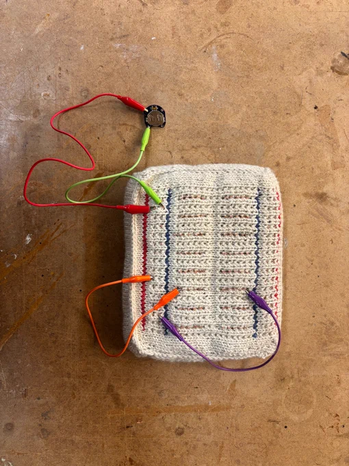 An 8 x 10inch handknitted breadboard with conductive thread and alligator clips