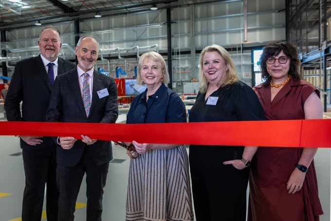 From left to right: Terry McEvoy, Alec Cameron, Peggy O'Neal, Mish Eastman and Kylie Dillon stand in front of a large red ribbon at RMIT's new Trades Innovation Centre.