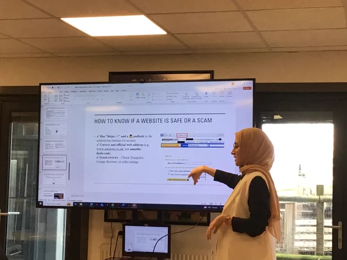Instructor going through a presentation slide about 'How to know if a website is safe or a scam'
