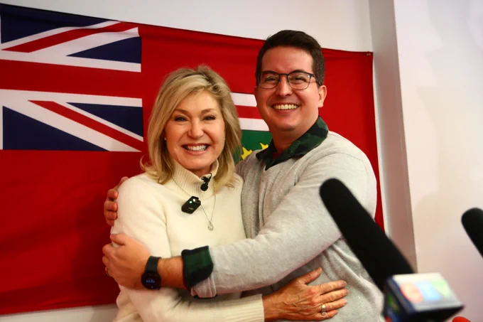 Bonnie Crombie and Brandon Bay hugging in front of the Ontario flag