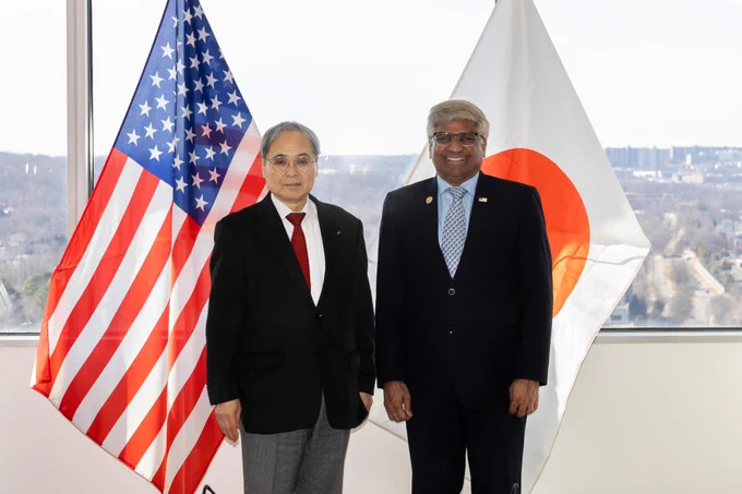 NSF Director Sethuraman Panchanathan and Hashimoto Kazuhito,  Japan Science and Technology Agency (JST) president stand side by side in front of the U.S. and Japanese flags, posing for a photo.