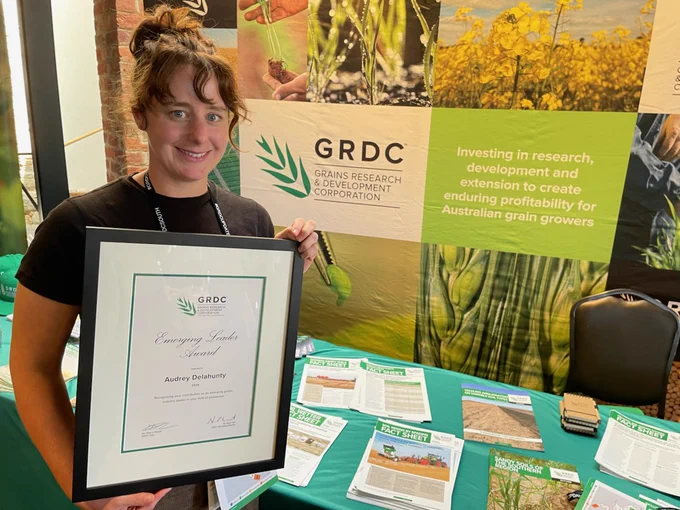 Audrey Delahunty holds a framed certificate in front of GRDC exhibition stand. 