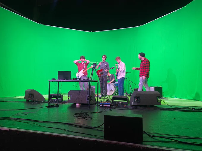 The band in front of a green screen 