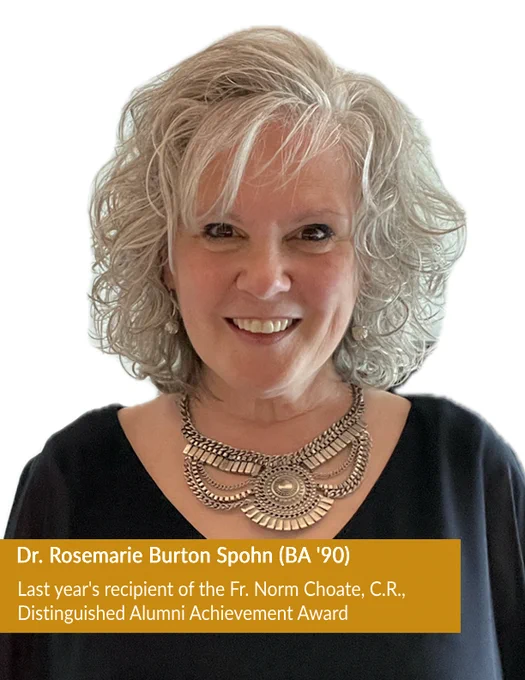 Dr. Rosemarie Burton Spohn, BA '90,  is the last year's recipient of the Fr. Norm Choate, C.R., Distinguished Alumni Achievement award. She smiles directly at the camera while wearing a black top and a statement silver necklace. The background is white, emphasizing her cheerful expression.