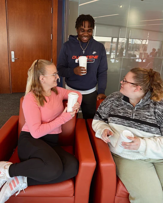 Students smiling next to each other and holding coffee cups