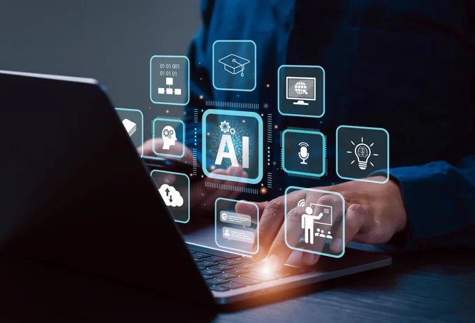 A person typing on a laptop with glowing AI-related icons floating above the keyboard, representing artificial intelligence, cloud computing, education, and innovation.