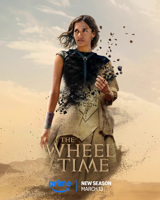 A poster of Egwene al'Vere (Madeleine Madden) in The Wheel of Time Season 3. Stood in a desert landscape, her body and garments are beginning to dissolve. The Wheel of Time logo is center at the bottom of the image, with the Prime Video logo beneath and text reading: “New Season March 13”.