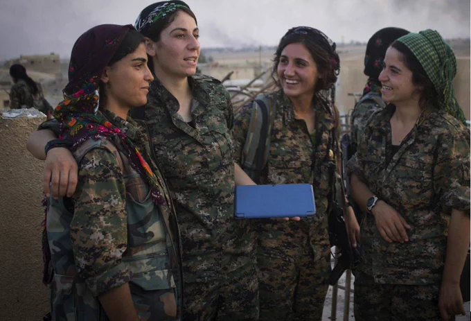 four members of the YPJ all-female militia smile at each other in Rojava, Syria