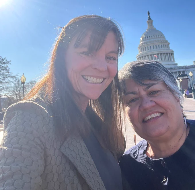 A photo of two people posed together for a selfie in front of the Capitol.