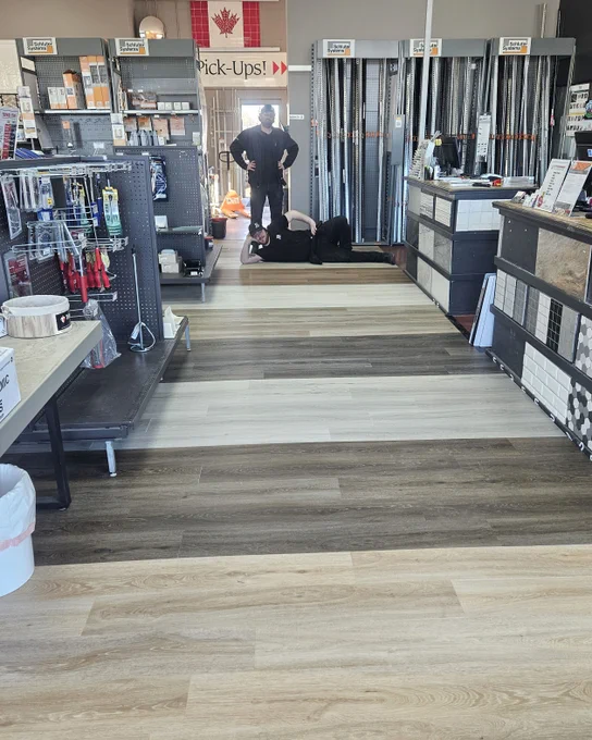 Same as pic before but a diffferent angle with a staff member lying on floor like Burt Reynolds modeling the luxury vinyl that the flooring is