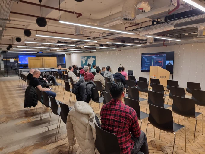 A few rows of chairs with some people on facing the board watching Paolo give a talk at Svelte London