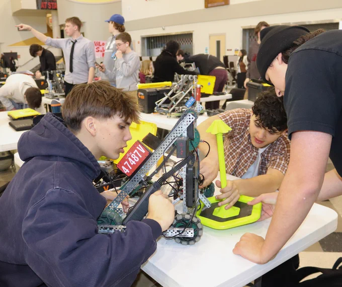 Three students work on a robot at a table