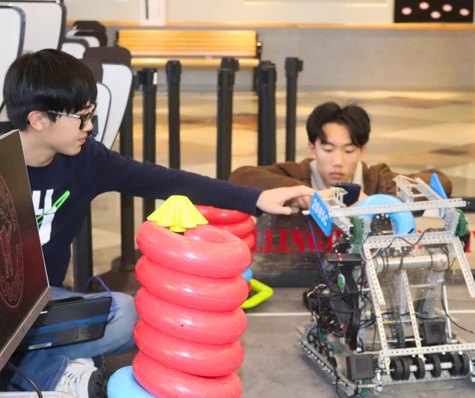 Two students work with a robot in the commons at BHS on a table