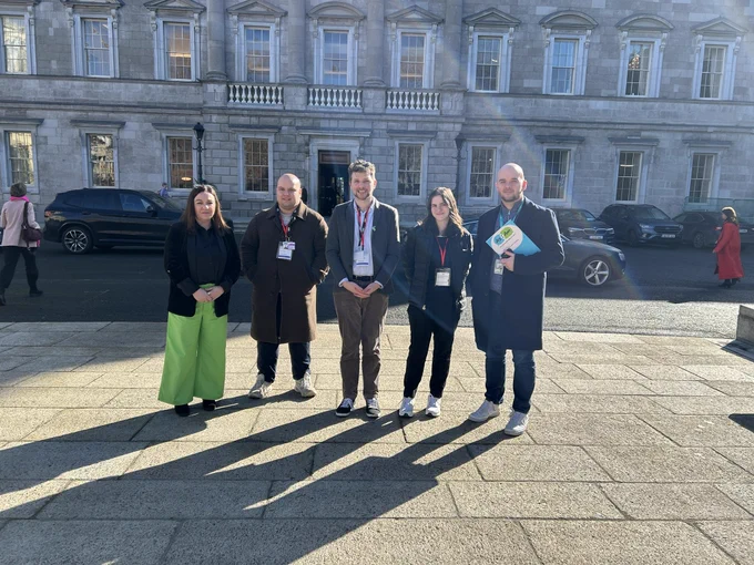 Five people standing outside Leinster House. This includes two TDs Jen Cummins and Aidan Farrell alongside three members of the Autism Charity As I Am