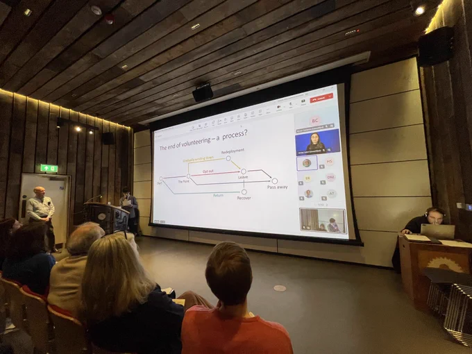 People sat in an auditorium and facing a screen with a presentation from the University of Newcastle.