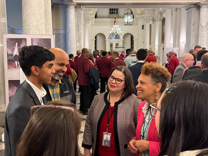 A  teen boy with his father and two Maryland State Delegates at the Maryland State House in Annapolis, both women, one Black and older and one white and middle-aged.
