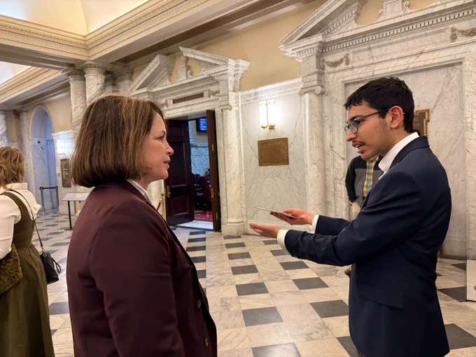 A teen boy with a white, female State Delegate.