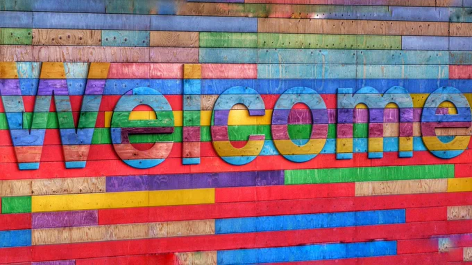 a colourful wooden art sign that says welcome