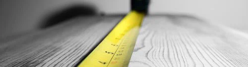 A tape measure shown measuring a piece of wood.