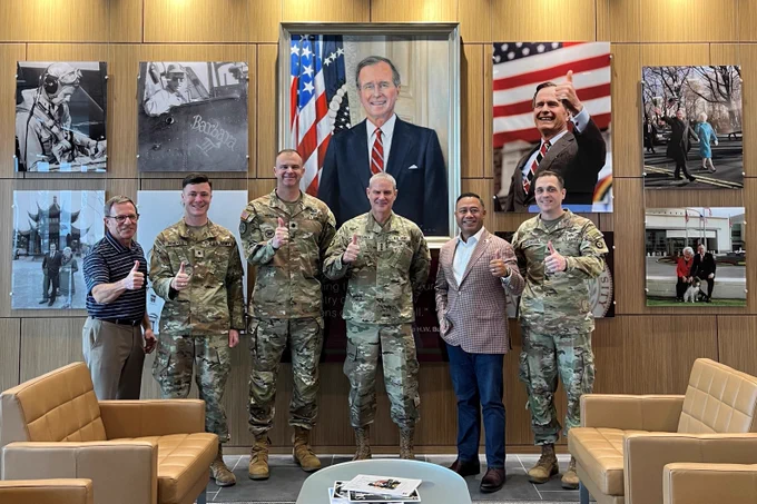 Six men standing in front of the George H.W. Bush tribute wall.