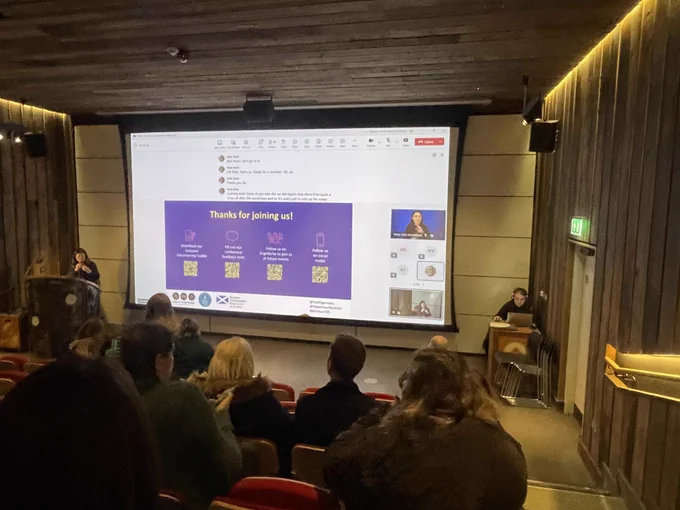 People sat in an auditorium and facing a screen with a slide that says "thanks for joining us!" with a call to fill out the event feedback form, download the Inclusive Volunteering Toolkit, follow Make Your Mark on Eventbrite and follow Make Your Mark on social media.