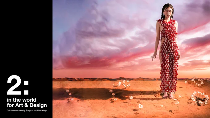 A digital artwork of a model standing in a desert landscape under a dramatic sunset sky. The model wears an avant-garde dress adorned with red key-like embellishments. White flowers sprout from the sand around her. On the left side of the image, bold text reads: "2: in the world for Art & Design. QS World University Subject 2025 Rankings."