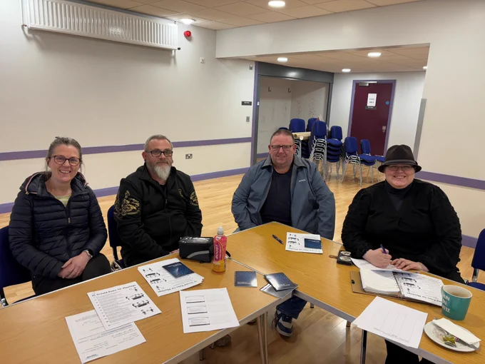 Photo of participants at Ballymena South Community Cluster’s Being an Effective Chairperson training - sitting at tables with papers in front of them, smiling to the camera.